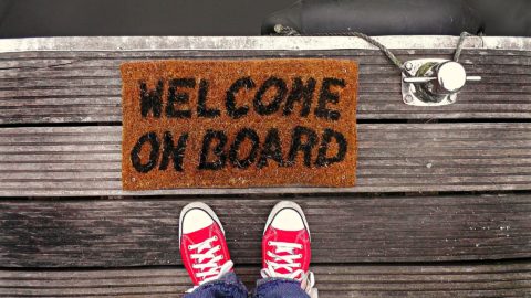 Füße vor Fußabtreter mit Aufschrift "Welcome on board"